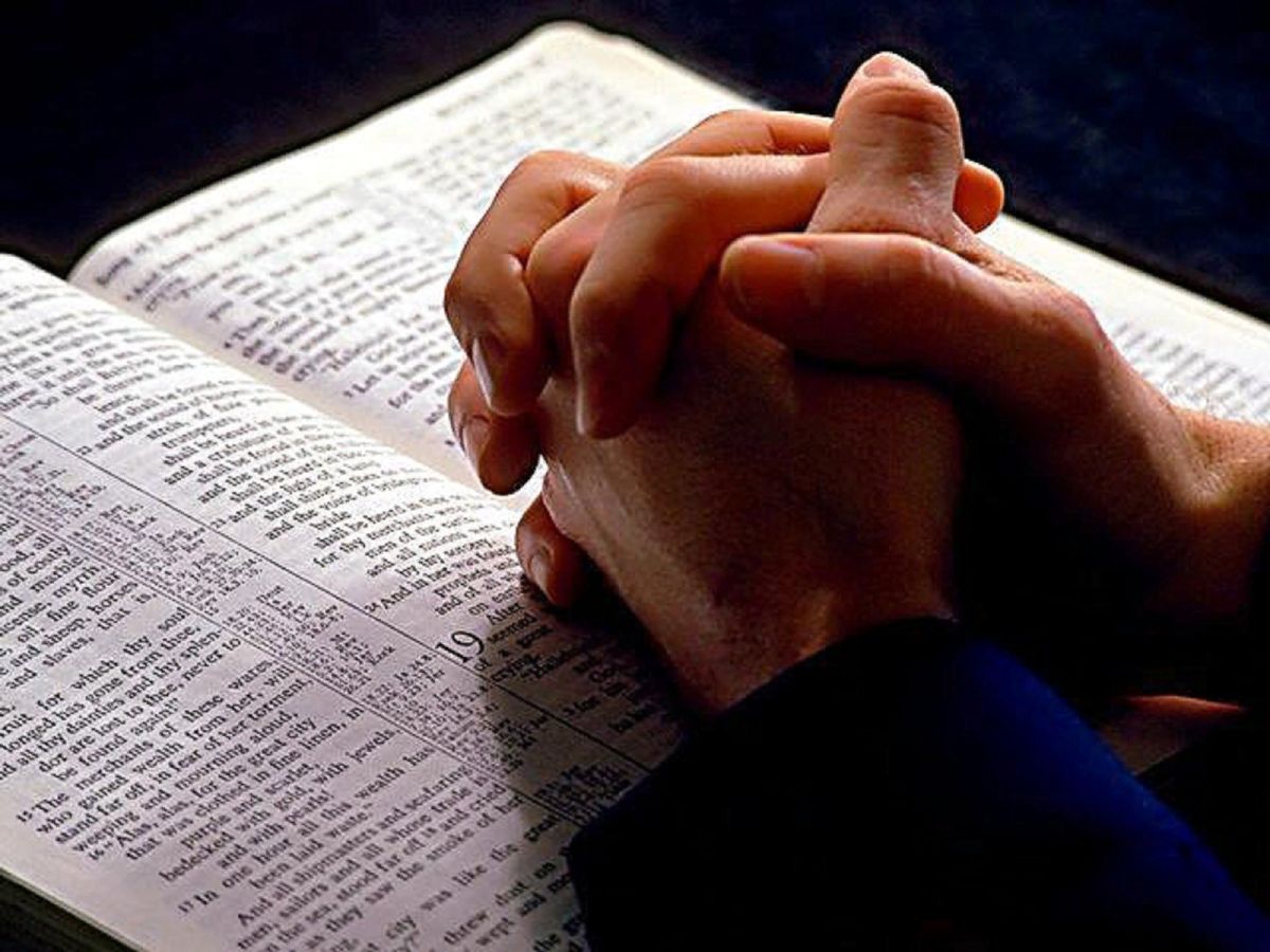 Человек молится с Библией